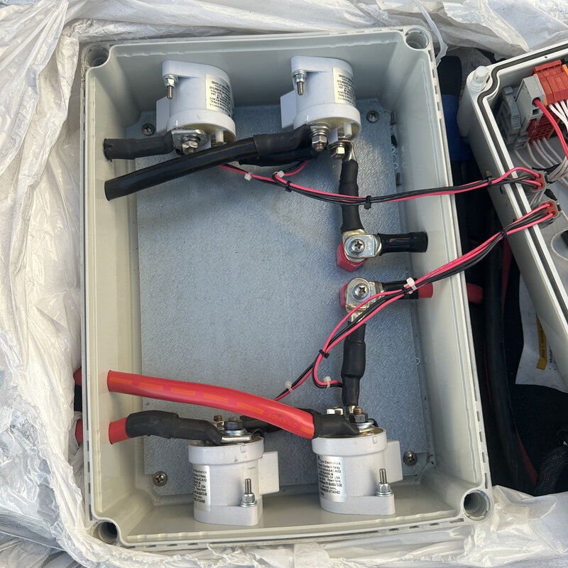 Enclosure containing four high-voltage contactors wired with orange and black cable