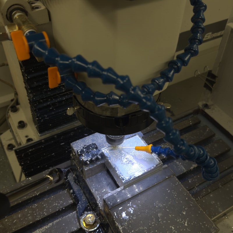 End mill cutting an aluminium part in a vice with coolant flowing